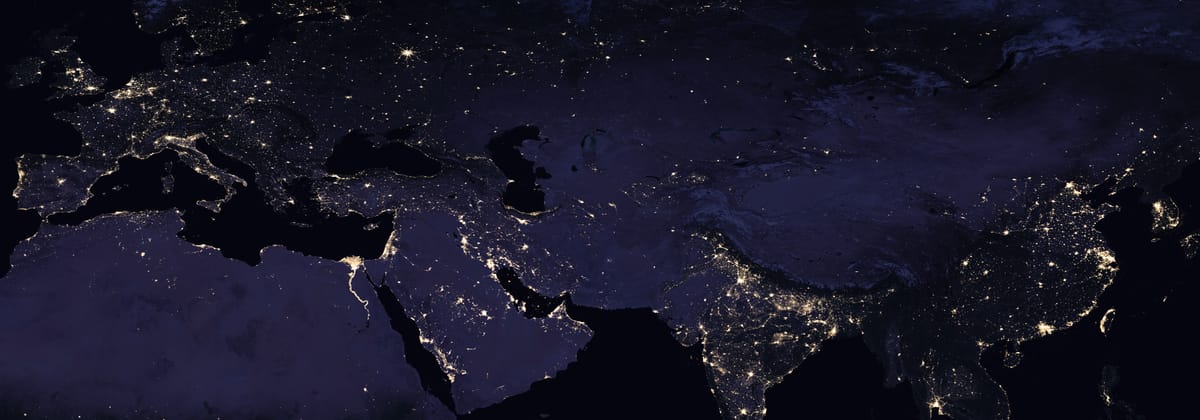 Europe and Asia from space at night, their city lights spread from London to Shanghai.